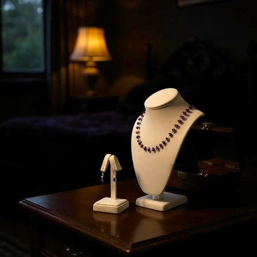 Necklace on a white bust and earring stand on a wooden table with a blurred background